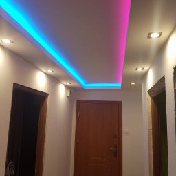 Ernest - Podwieszany sufit z oświetleniem LED w kolorach niebieskim i różowym w przedpokoju, widoczne drzwi wejściowe i ościeżnice.