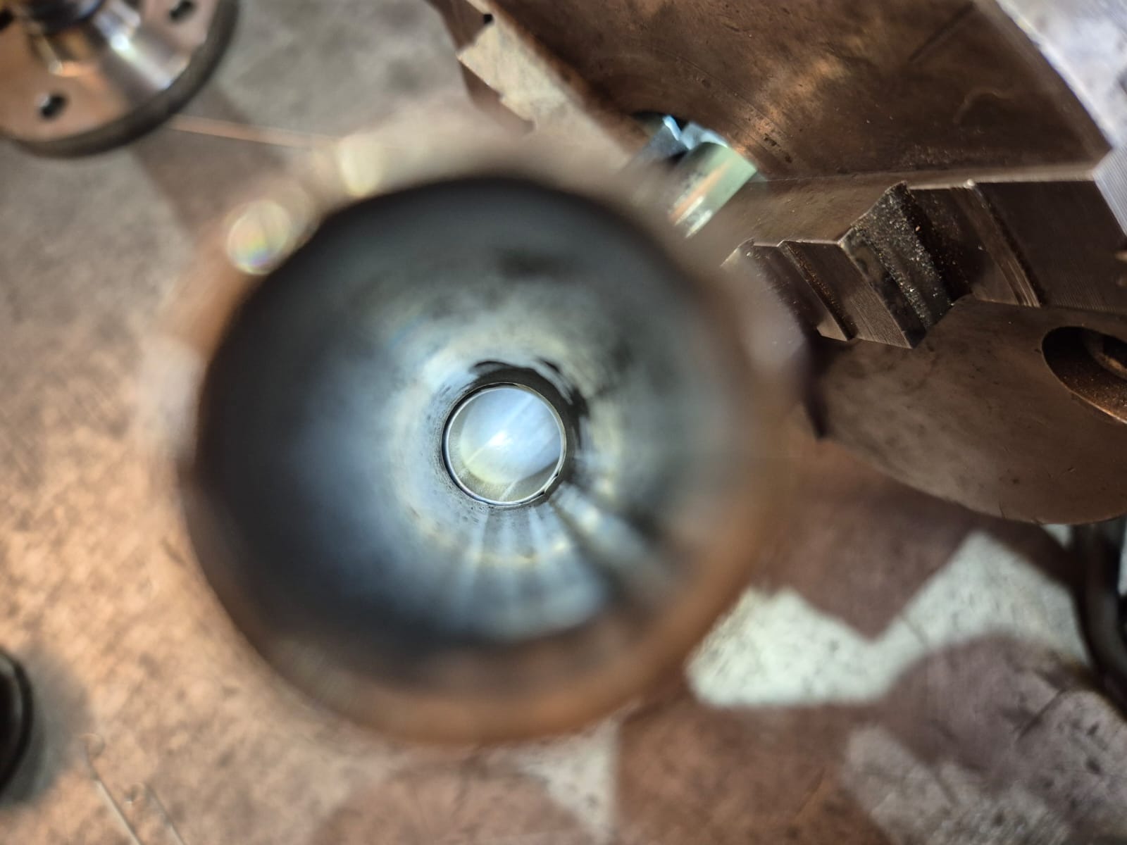 Wnętrze metalowej rury widzianej z bliska, z widocznymi śladami obróbki i elementami mocującymi na zewnątrz, co sugeruje etap produkcji lub naprawy.