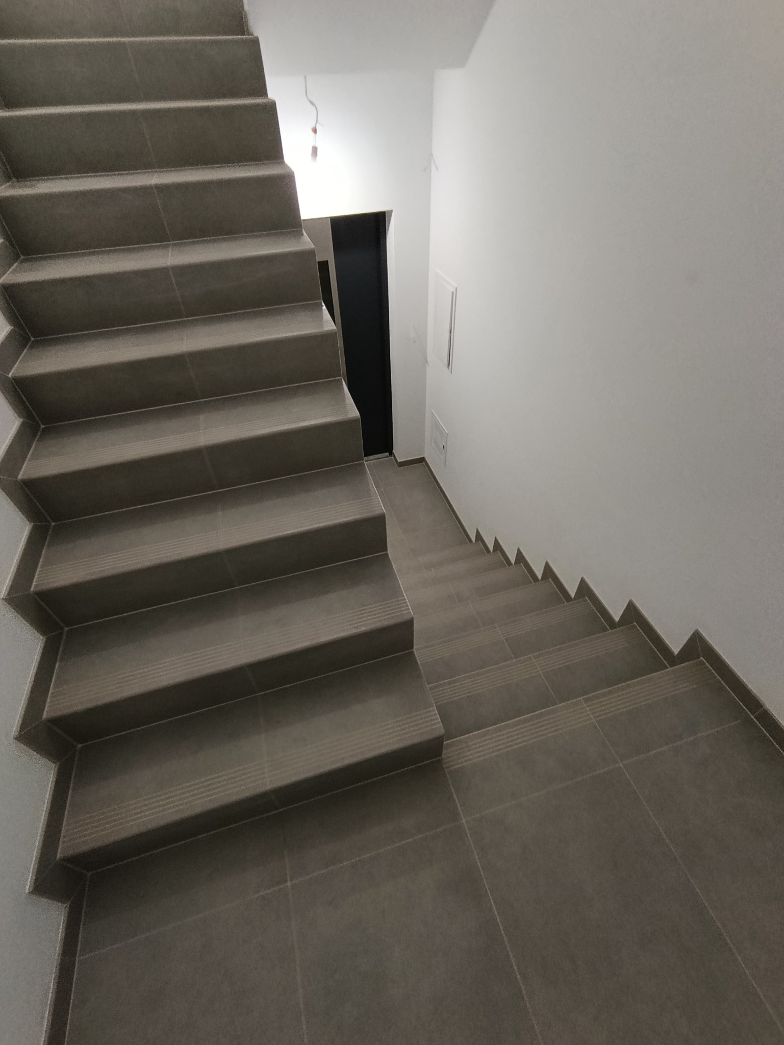 Wykończone schody z szarych płytek, z delikatnym wzorem na krawędziach stopni, w nowoczesnym wnętrzu w Zielonce. Minimalistyczny design.