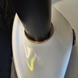 Domowa Harmonia - Błyszcząca, biała umywalka z czarną armaturą i złotymi detalami, po sprzątaniu. Widoczny fragment marmurowej ściany.