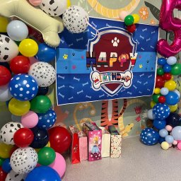 KinderParty MARTA MARCINOW - Dekoracja urodzinowa w stylu 'Psi Patrol' z balonami i prezentami na tle ściany w tropikalne wzory. Balon w kształcie cyfry 5.