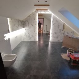 Perfect-bud - Wnętrze łazienki na poddaszu z szarą marmurkową podłogą i ścianami w biało-szare wzory. Widoczne narzędzia pracy, co sugeruje etap wykończeniowy.