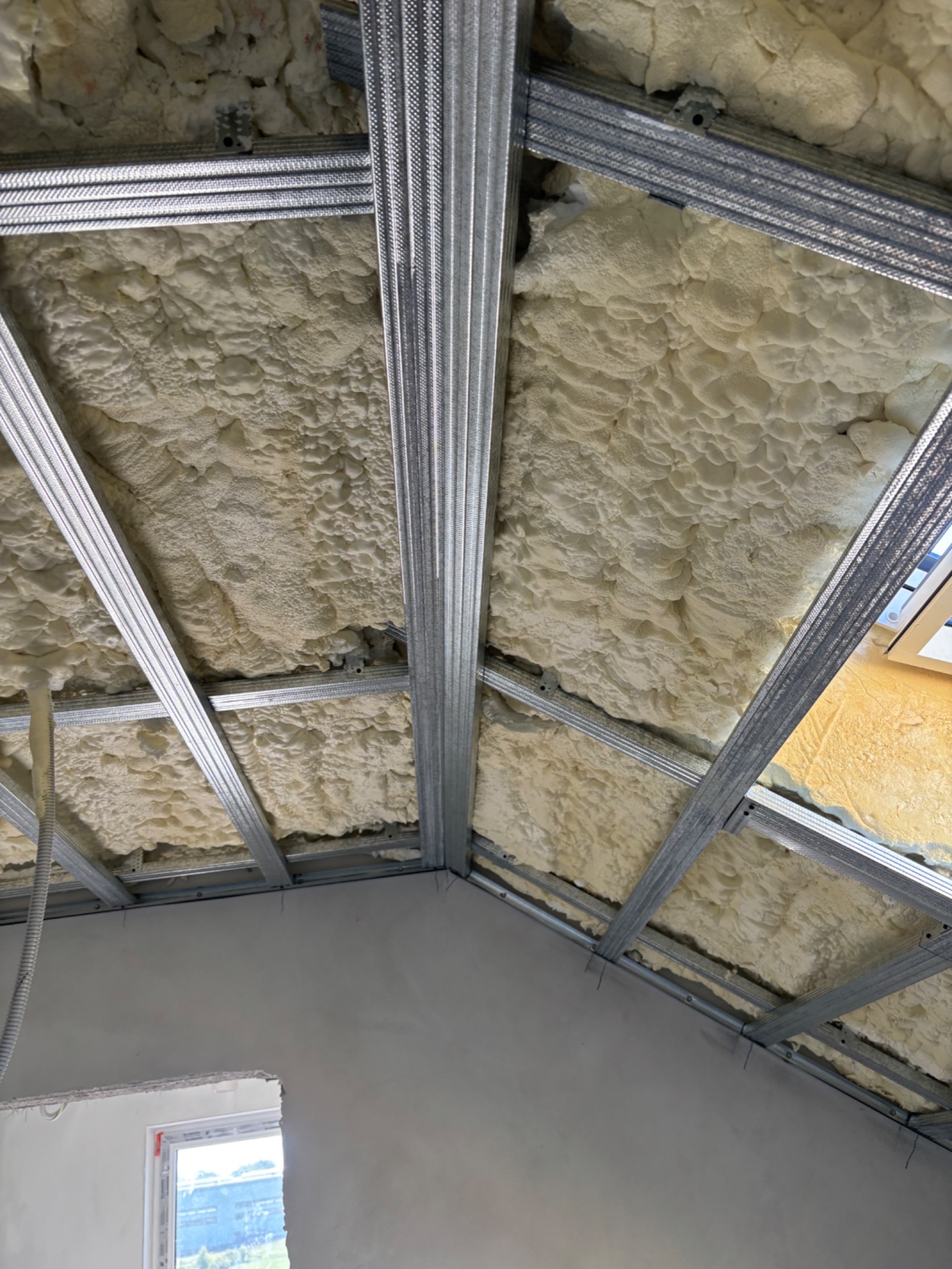 Ocieplenie poddasza pianą PUR z widoczną metalową konstrukcją nośną. Izolacja natryskowa na poddaszu.