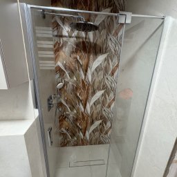 VASYL PAVLIUK Royal Remont - Kabina prysznicowa z deszczownicą i wzorzystą ścianą w odcieniach brązu i beżu. Widoczny odpływ liniowy i chromowana armatura. Wykończona łazienka.