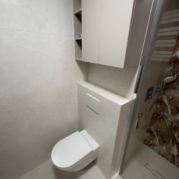 VASYL PAVLIUK Royal Remont - Nowoczesna łazienka z podwieszaną toaletą, szafką nad nią i kabiną prysznicową z wzorzystą ścianą. Jasne płytki na ścianach i podłodze. Minimalistyczny design.