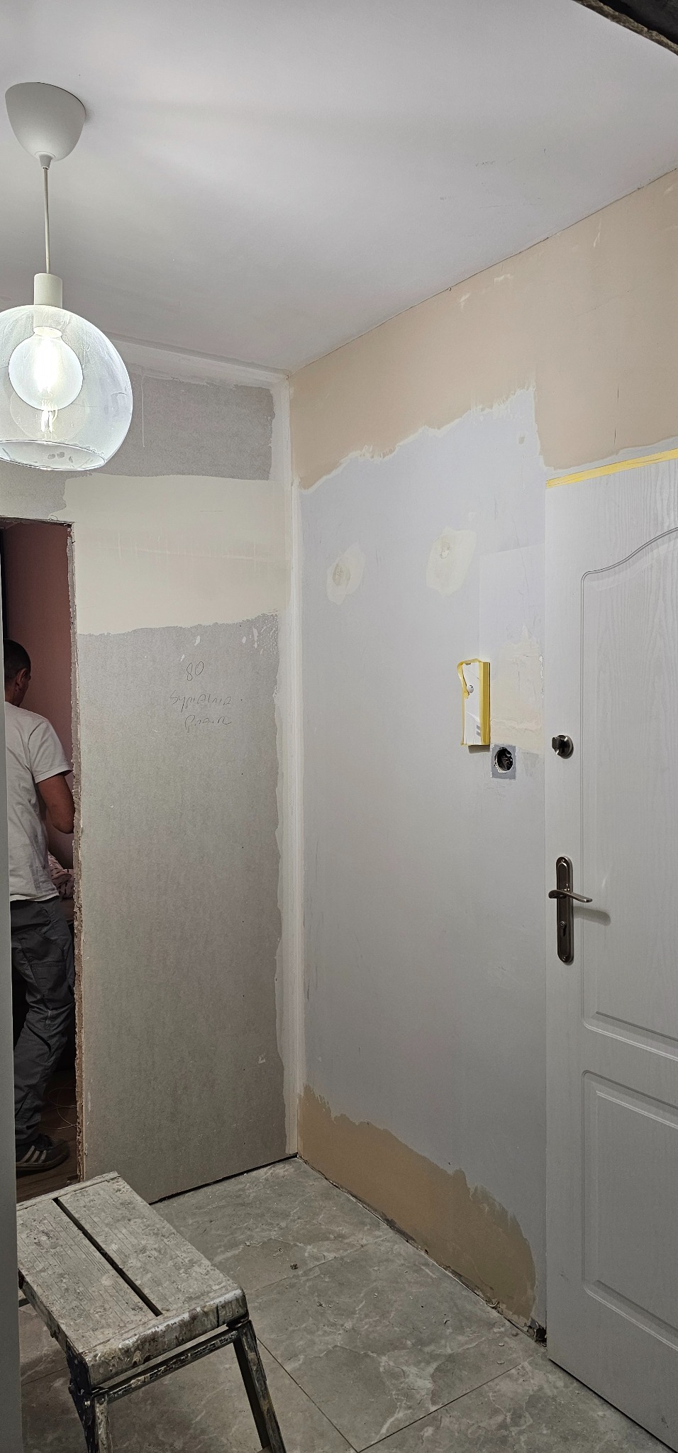 Wnętrze w trakcie prac wykończeniowych: ściany po szpachlowaniu, widoczna płyta karton-gips, przygotowanie do malowania. Drabina malarska i lampa wisząca w kadrze.