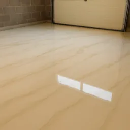 Jasna, beżowa posadzka z efektem marmuru w garażu, odbijająca światło okna. Widoczna brama garażowa i fragment ściany z szarych bloczków.