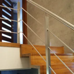 Drewniane schody z metalowymi poręczami w nowoczesnym wnętrzu, widok z dołu, widoczna fragment drzwi z poziomymi listwami.