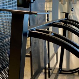 MDA DAMIAN MALISZEWSKI - Metalowa konstrukcja z perforowanymi elementami, świeżo po malowaniu proszkowym, widoczne spawy i elementy montażowe.