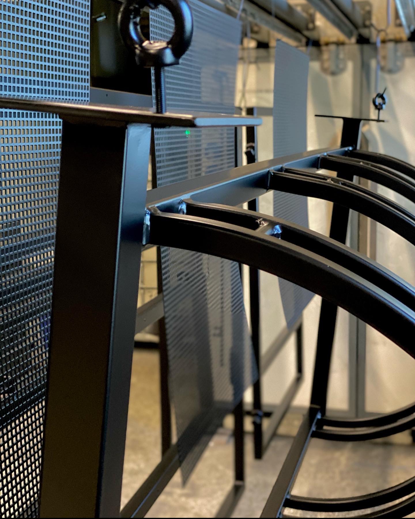 Metalowa konstrukcja z perforowanymi elementami, świeżo po malowaniu proszkowym, widoczne spawy i elementy montażowe.