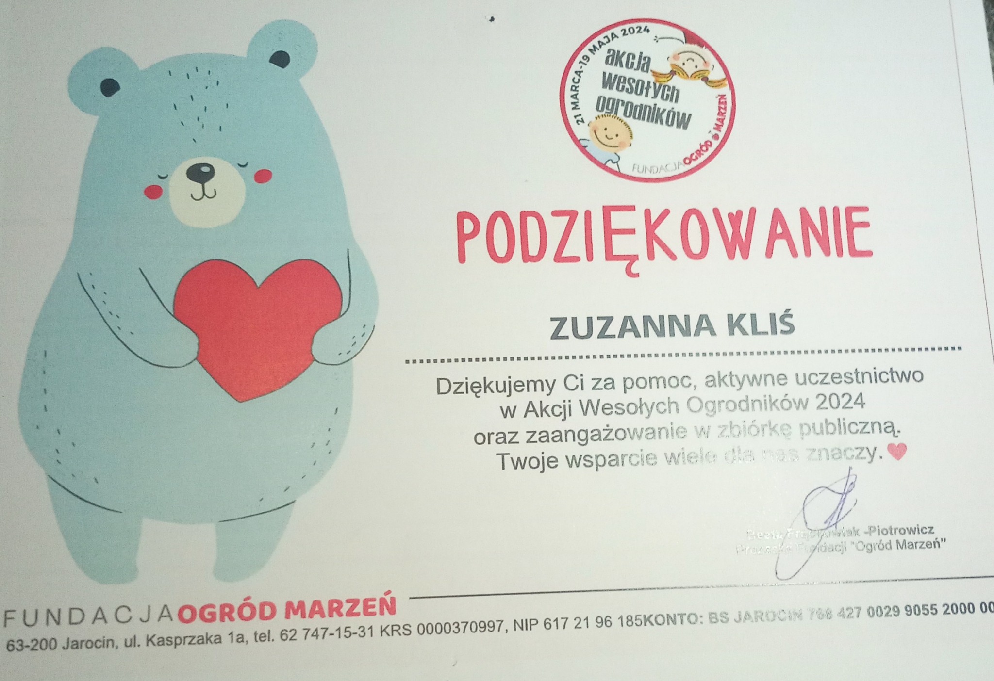 Podziękowanie dla Zuzanny Kliś od Fundacji Ogród Marzeń za udział w Akcji Wesołych Ogrodników 2024, z ilustracją niebieskiego misia trzymającego czerwone serce.