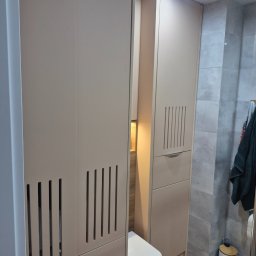 Ytsenko Dmytro - Beżowa szafa łazienkowa na wymiar z pionowymi żłobieniami, wkomponowana w małą przestrzeń nad toaletą, z szarą glazurą i drewnopodobną podłogą.