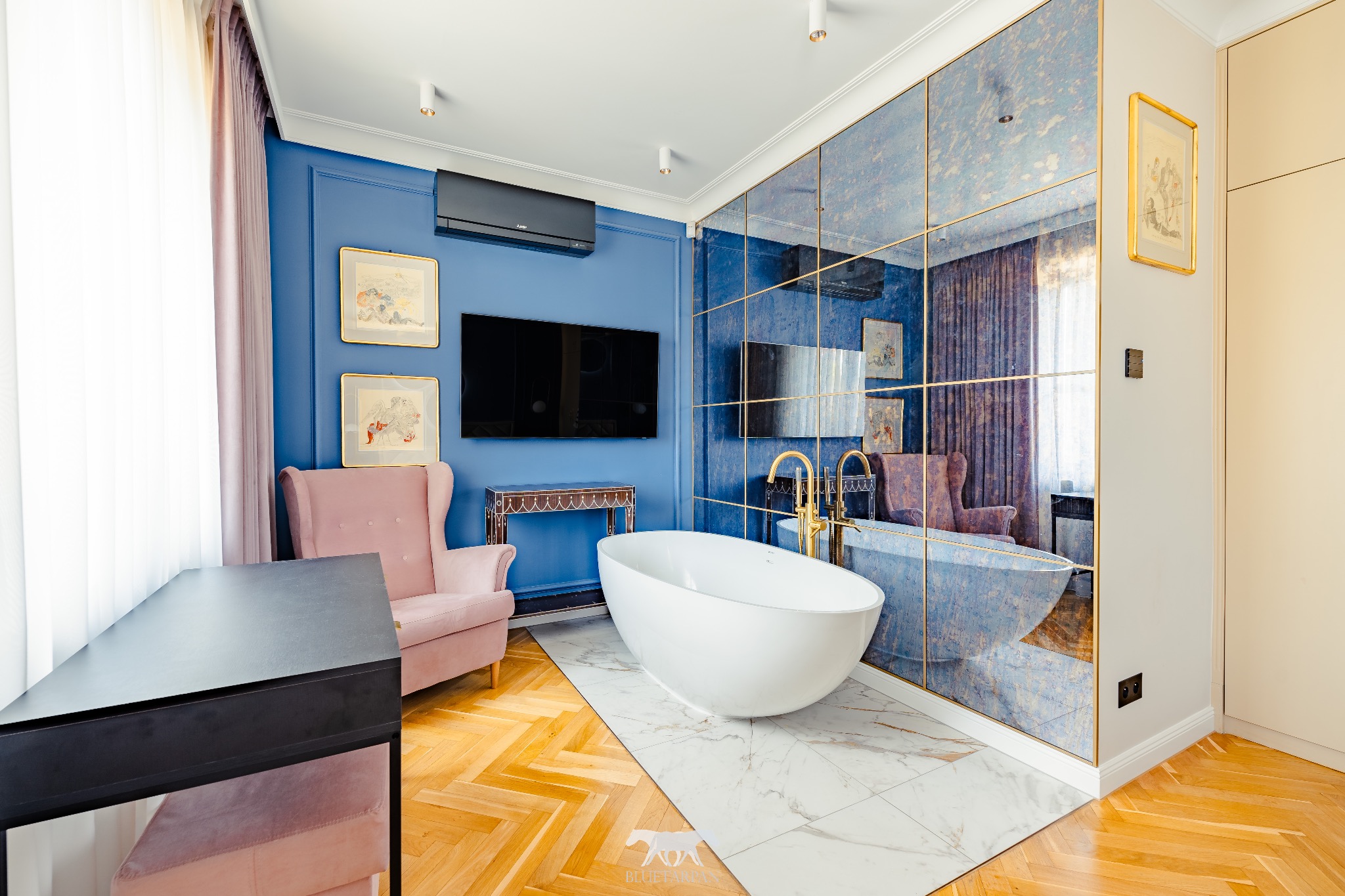 Elegancka łazienka z wolnostojącą wanną na marmurowej posadzce, lustrzana ściana i parkiet w jodełkę. Akcenty różu i złota dodają luksusowego charakteru.
