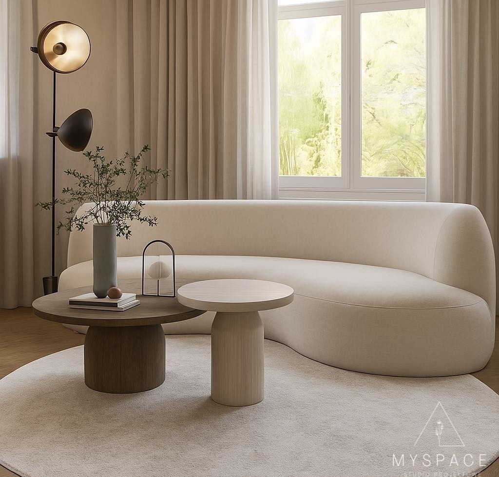 Nowoczesny salon w beżach: zaokrąglona sofa, okrągłe stoliki kawowe, lampa podłogowa i duże okno z widokiem na zieleń. Minimalistyczny design wnętrza.