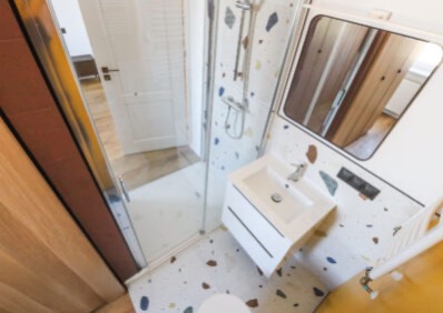 Nowoczesna łazienka z kabiną prysznicową, umywalką i lustrem. Uwagę zwracają płytki w stylu lastryko na podłodze i ścianach. Widok z góry.