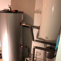 HELIUS ENERGY SPÓŁKA Z OGRANICZONĄ ODPOWIEDZIALNOŚCIĄ - Dwa zbiorniki, w tym jeden marki Galmet, połączone rurami z izolacją termiczną, w pomieszczeniu technicznym. Widoczne zawory i elementy instalacji grzewczej.