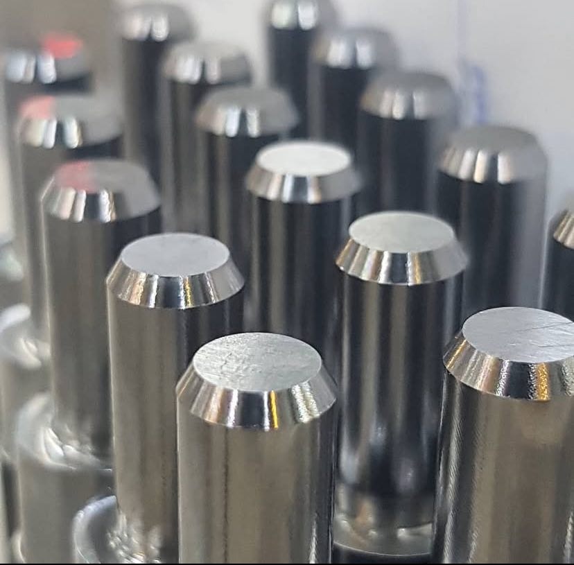 Precyzyjnie obrobione metalowe trzpienie CNC z fazowanymi krawędziami, tworzące powtarzalny wzór, ukazujące detale obróbki skrawaniem.