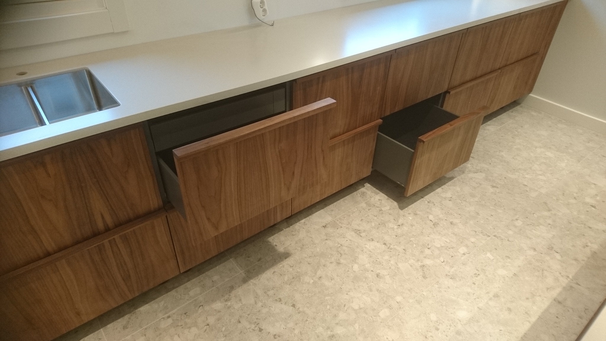 Nowoczesna zabudowa kuchenna z drewnianymi frontami i otwartymi szufladami, widoczny zlew. Realizacja z Skępe.