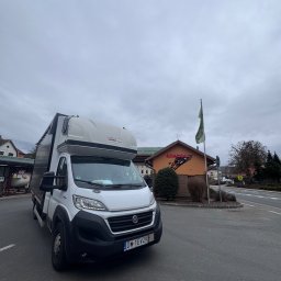 Kewin Grzybowski - Biały bus dostawczy Fiat Ducato z wysoką zabudową, zaparkowany na parkingu przed budynkiem z logo 'ATAC OIL' w pochmurny dzień. Widoczna tablica rejestracyjna.