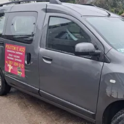 Szary samochód serwisowy z naklejką 'Pogotowie AGD' z numerem telefonu, zaparkowany na zewnątrz. Widoczne logo firmy na drzwiach.