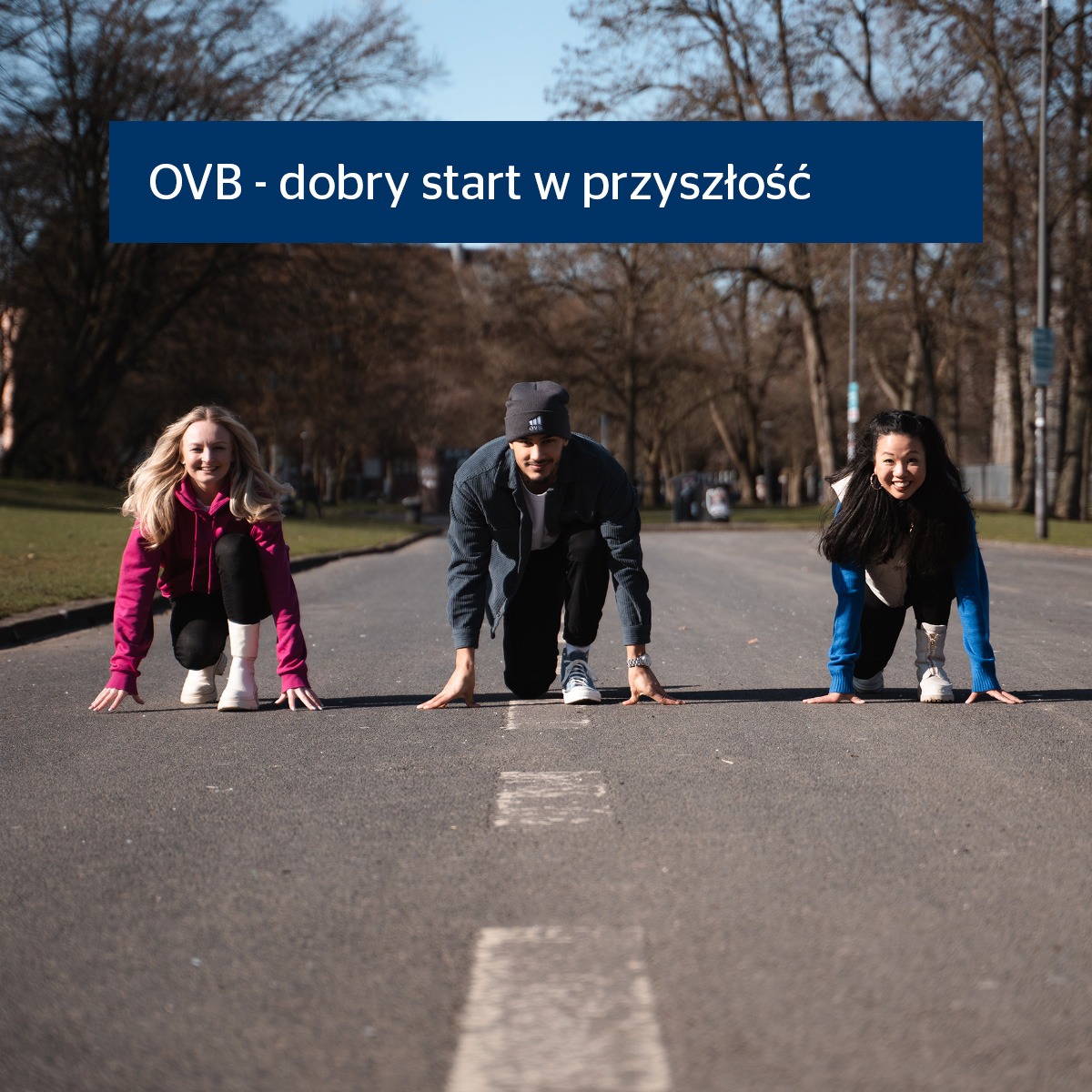 Trzy osoby w pozycji startowej na drodze z napisem 'OVB - dobry start w przyszłość', sugerujące gotowość do działania i planowania finansowego.