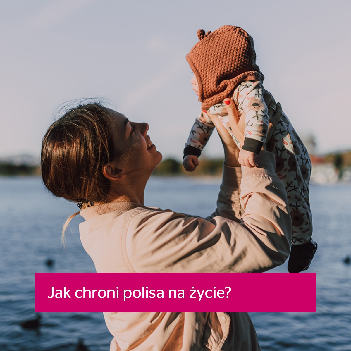 Uśmiechnięta kobieta podnosi w górę małe dziecko na tle jeziora; różowy baner z tekstem 'Jak chroni polisa na życie?'.