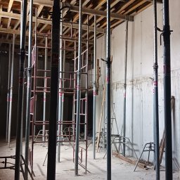 NadzórTECH Dominik Dzierwa - Wnętrze w trakcie budowy: betonowe ściany, stalowe podpory stropowe z regulacją wysokości, widoczne drewniane szalunki stropu. Etap wylewania stropu.