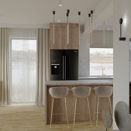 Michał Wilkosiński Conifer Media - Nowoczesna kuchnia z wyspą, drewnianymi szafkami i czarną lodówką. Widok na jezioro przez okno. Krzesła barowe z złotymi nogami. Dekoracje ścienne z motywami roślinnymi.