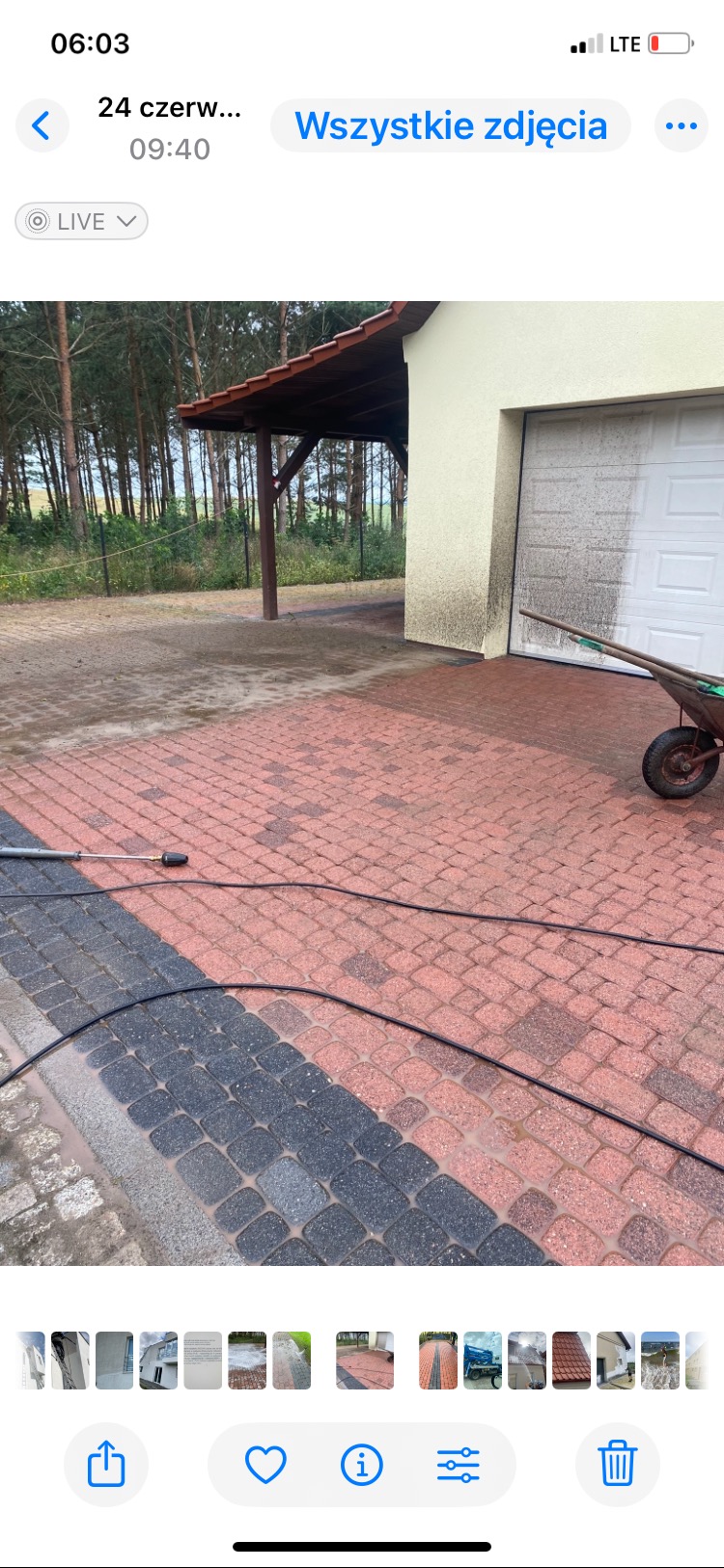 Częściowo umyta kostka brukowa w kolorze czerwono-szarym, z widocznym wężem ciśnieniowym i fragmentem elewacji budynku z garażem, ukazująca efekt czyszczenia.