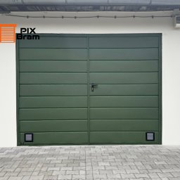 PixBram Dawid Kasprzyk - Zielona, dwuskrzydłowa brama garażowa z poziomymi panelami, czarną klamką i kratkami wentylacyjnymi u dołu, na tle białej ściany i szarej kostki brukowej.