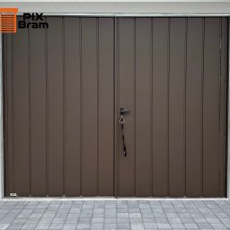 PixBram Dawid Kasprzyk - Dwuskrzydłowa, brązowa brama garażowa z pionowymi panelami i czarną klamką, na której wiszą klucze. Widoczna kostka brukowa przed bramą i fragment elewacji.