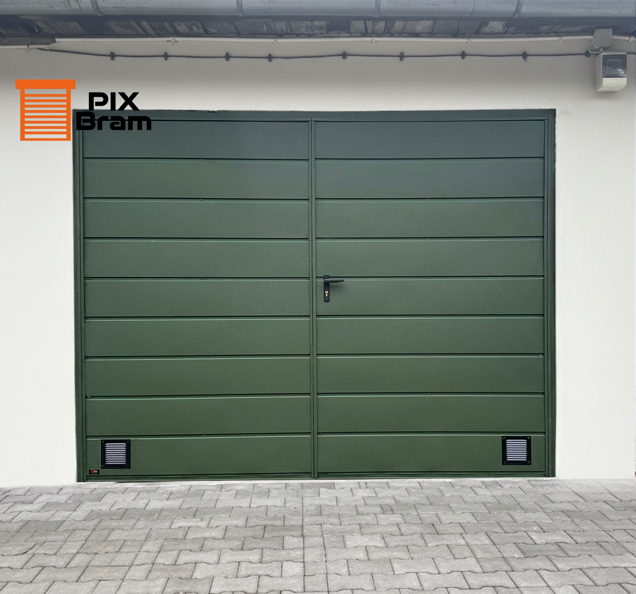 Zielona, dwuskrzydłowa brama garażowa z poziomymi panelami, czarną klamką i kratkami wentylacyjnymi u dołu, na tle białej ściany i szarej kostki brukowej.