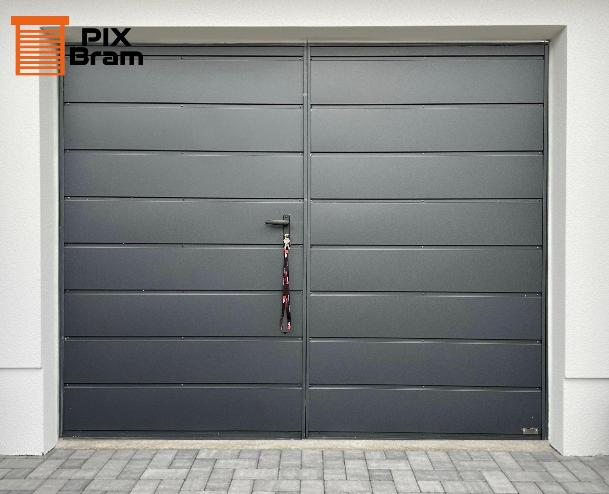 Szara, segmentowa brama garażowa z poziomymi panelami, z klamką i kluczami. Widoczny fragment elewacji i kostki brukowej. Minimalistyczny design.