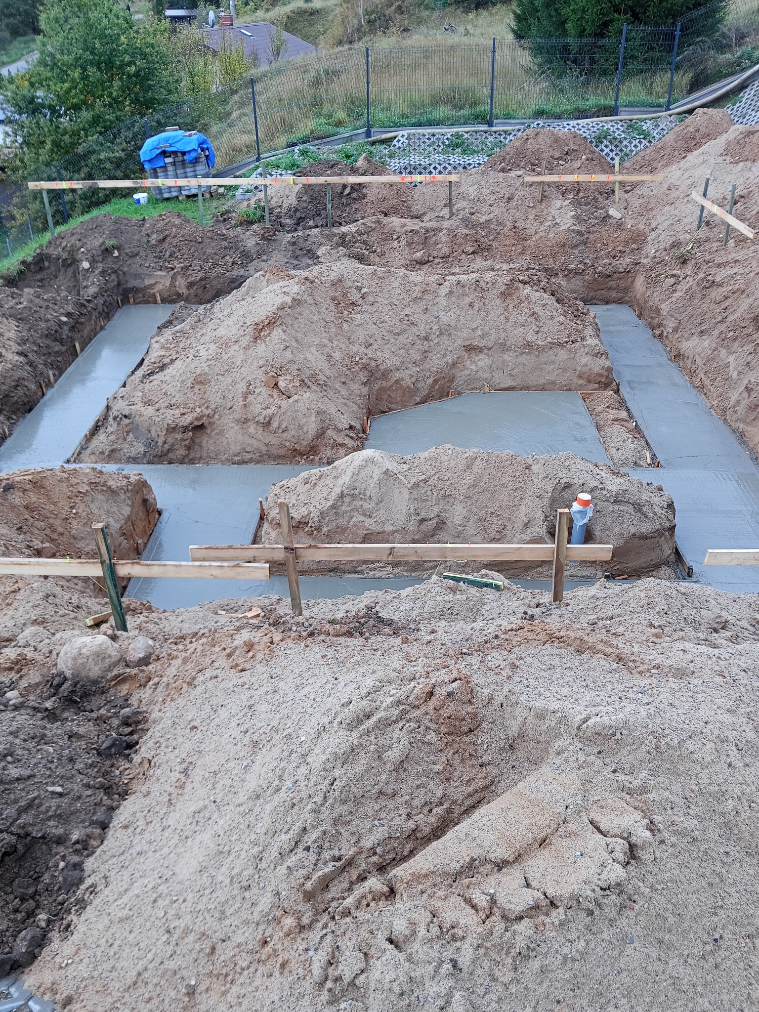 Zalane fundamenty pod budowę domu w Rąbinie. Widoczne szalunki i świeży beton. Grunt wokół wykopu. Prace ziemne w toku, przygotowanie do dalszych etapów budowy.