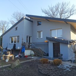 M&M HOUSE - Szara elewacja domu jednorodzinnego w Opolu po malowaniu. Widoczne narzędzia i materiały malarskie. Uwagę zwraca nowoczesna bryła budynku i minimalistyczny styl.