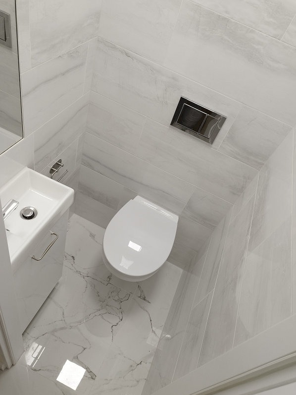 Jasna łazienka z marmurowymi płytkami, wiszącą toaletą i umywalką. Minimalistyczny design z chromowanymi akcentami i subtelnym oświetleniem.