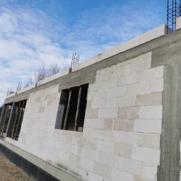 Rafał Rosiński - Ściany z betonu komórkowego w trakcie budowy domu jednorodzinnego w Mirowie Starym. Widoczne otwory okienne z drewnianymi stemplami i zbrojenie na górze ściany.