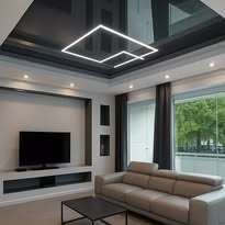 Nowoczesny salon z czarnym, błyszczącym sufitem i geometrycznym oświetleniem LED. Beżowa kanapa i minimalistyczny design wnętrza.