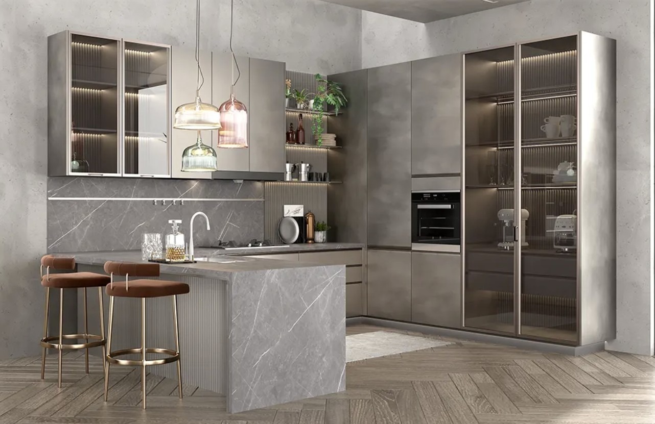 Nowoczesna kuchnia z wyspą, szarym blatem imitującym marmur i wysokimi krzesłami barowymi. Szklane witryny szafek podświetlone. Wiszące lampy o ciekawym designie.