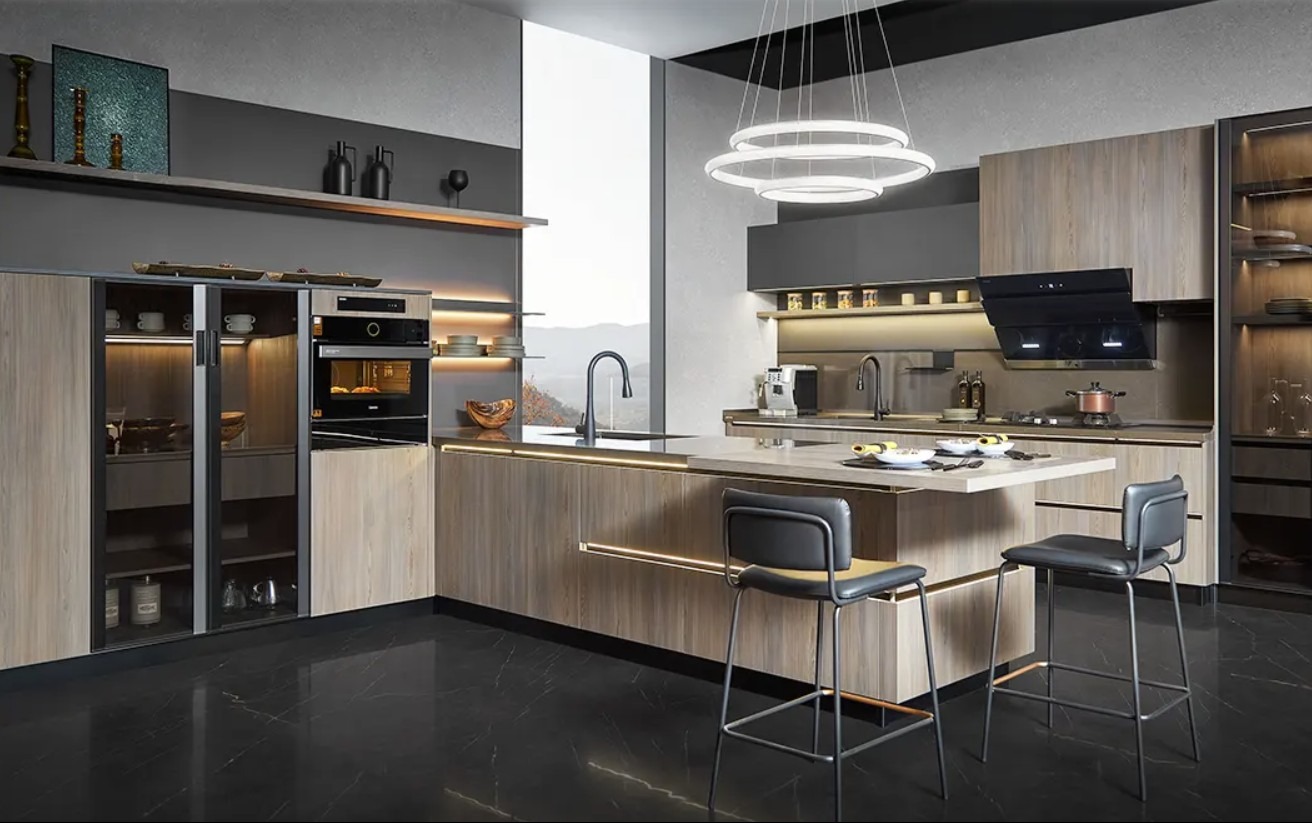 Nowoczesna kuchnia na wymiar z wyspą, drewnianymi frontami i czarnym blatem. Oświetlenie LED podkreśla elegancję. Widoczne krzesła barowe i sprzęt AGD.