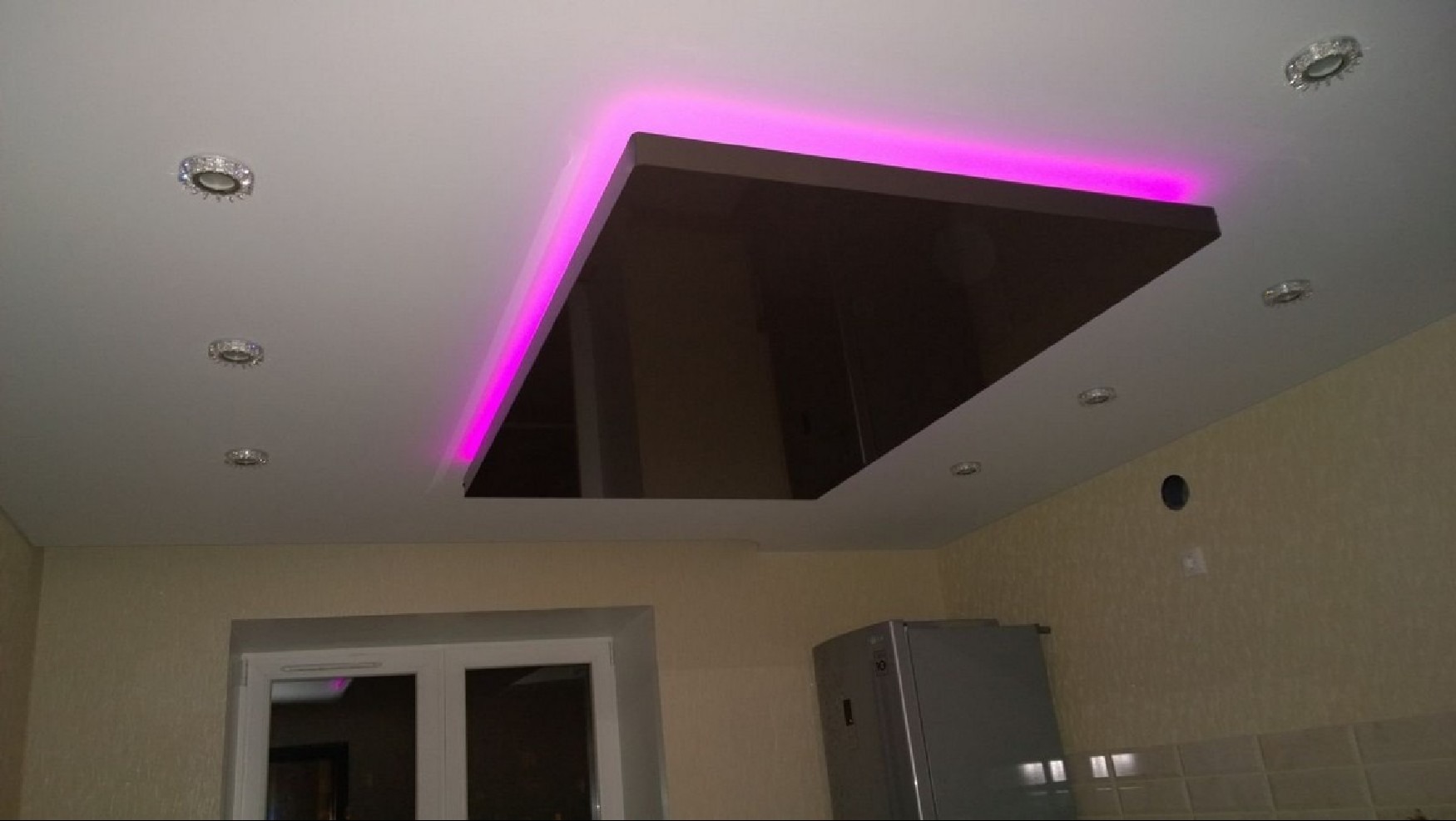 Błyszcząca, brązowa powierzchnia sufitu z podświetleniem LED w kolorze fuksji, wkomponowana w biały sufit, w mieszkaniu w Bydgoszczy. Dodatkowe oświetlenie punktowe.