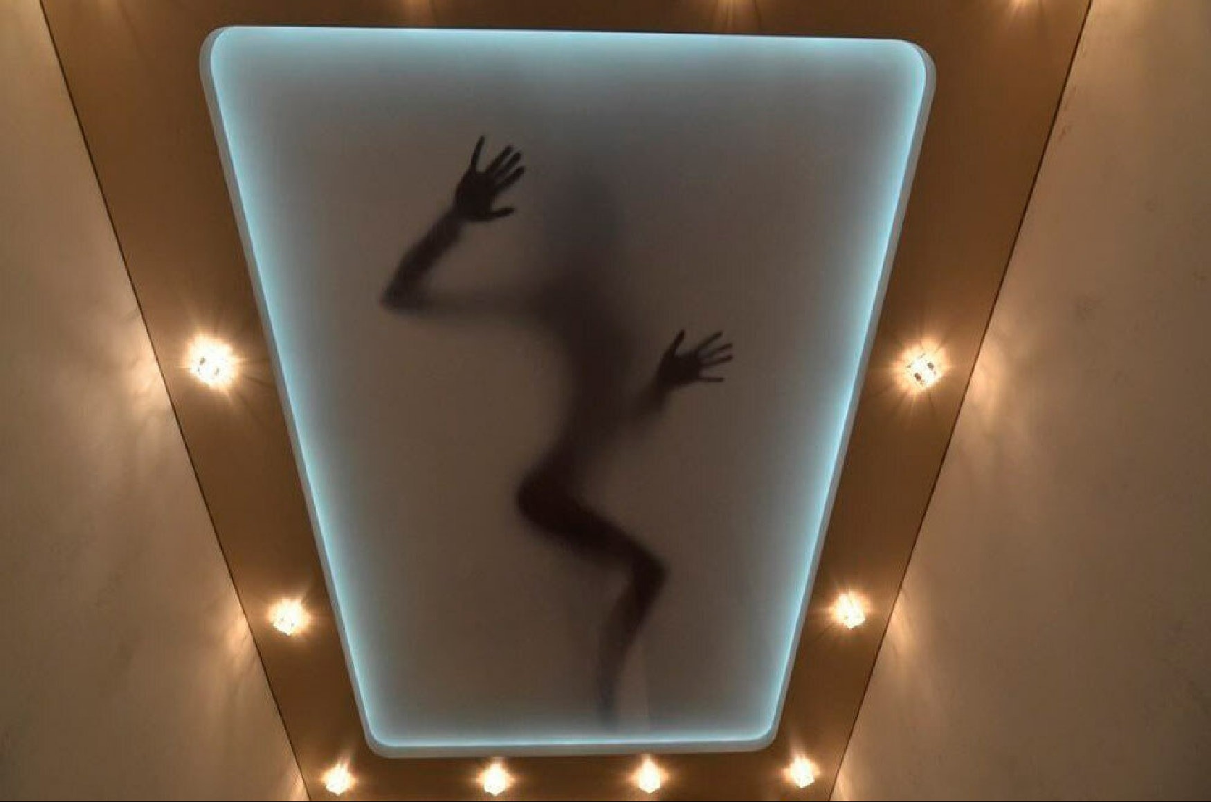 Oryginalny sufit podwieszany z podświetleniem LED i sylwetką osoby. Geometryczny kształt, ciepłe oświetlenie punktowe, nietypowy design.