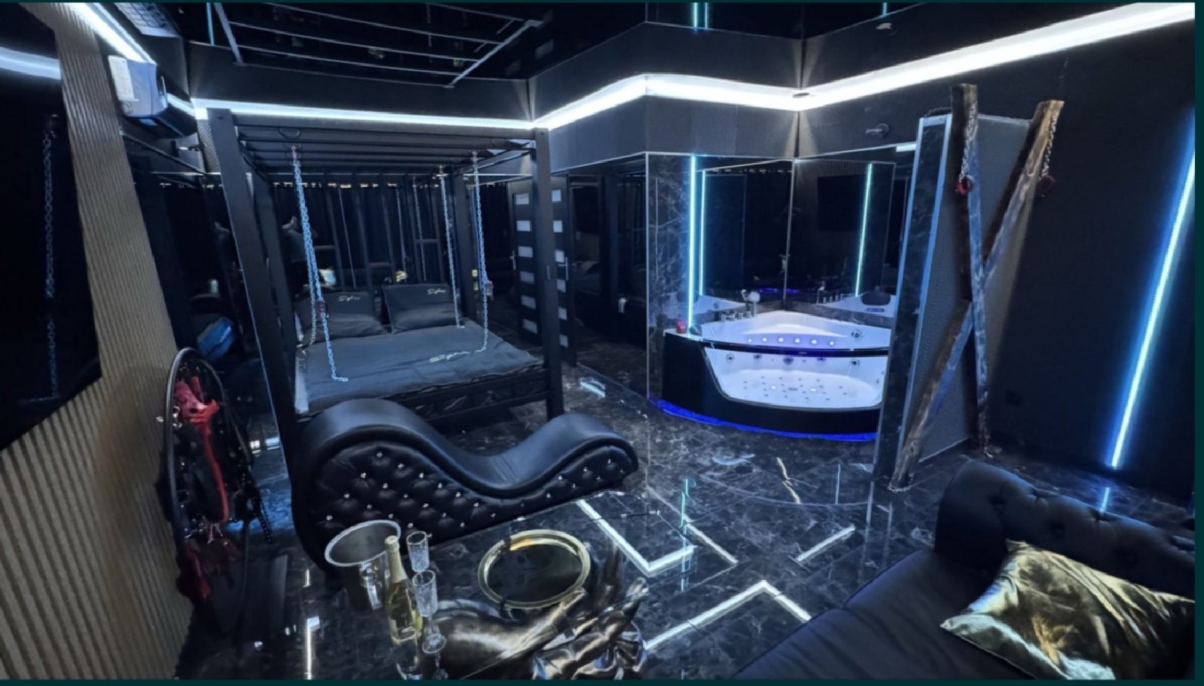 Nowoczesny pokój z luksusowym wyposażeniem: łóżko na łańcuchach, jacuzzi z podświetleniem LED i elegancka sofa w ciemnej tonacji. Nietypowy design.