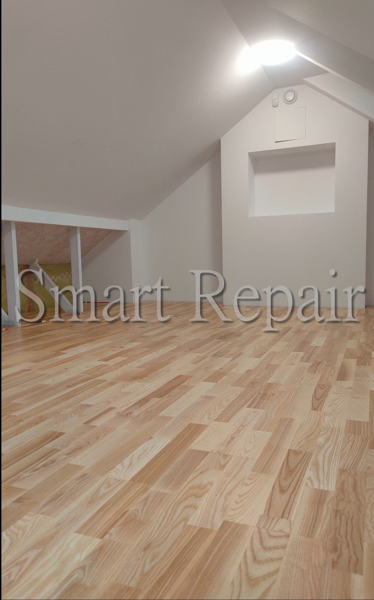 Jasna, drewniana podłoga w wykończonym pokoju na poddaszu z oknem w ścianie szczytowej. Minimalistyczny styl, świeżo po remoncie.