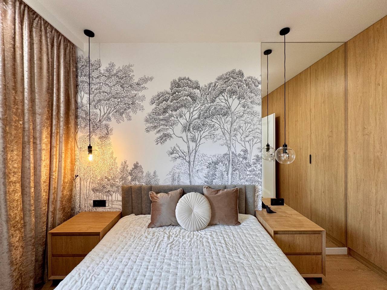 Stylowa sypialnia z fototapetą leśną, drewnianą zabudową i lampami wiszącymi. Neutralne kolory, tekstylia. Aranżacja wnętrza z dbałością o detale.