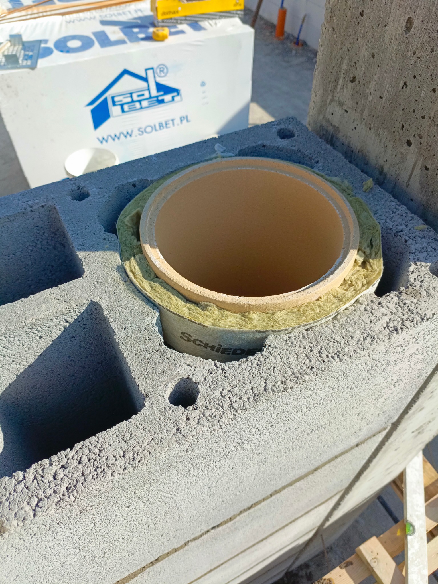 Murowanie komina systemowego Schiedel z bloczków Solbet. Widoczna wełna izolacyjna. Praca w toku.