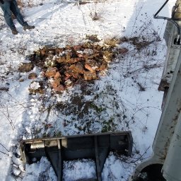 PNEUMATIC HYDRO - Zimowy krajobraz z wykopem gruzu i fragmentem maszyny budowlanej. W tle widoczny pracownik w odblaskowej kamizelce i mały budynek.