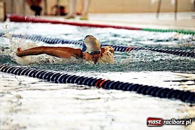 Pływaczka w czepku i okularach płynie stylem dowolnym w basenie, oddzielona linami torów. Dynamiczne ujęcie z bliska, widoczne pluski wody.