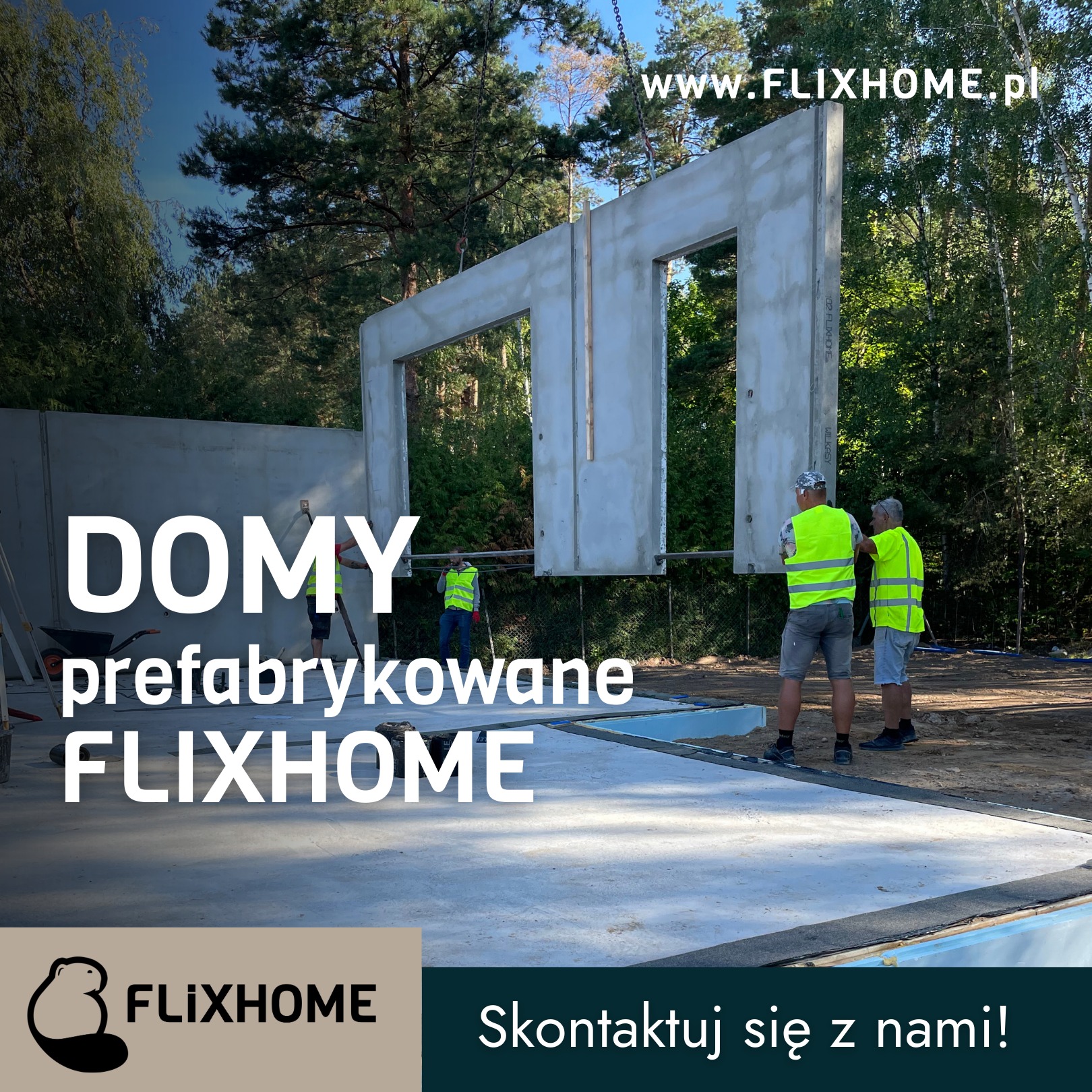 Montaż prefabrykowanego elementu domu Flixhome. Dwóch pracowników w kamizelkach odblaskowych nadzoruje proces. W tle las i częściowo wzniesiona ściana budynku.