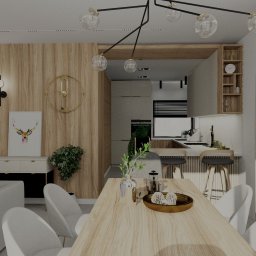 Justyna Projektuje - Justyna Krupa - Wnętrze otwartej przestrzeni: salon z sofą i jadalnia z drewnianym stołem, płynnie przechodzące w kuchnię z barkiem. Nowoczesny design z elementami drewna i minimalistycznym oświetleniem.